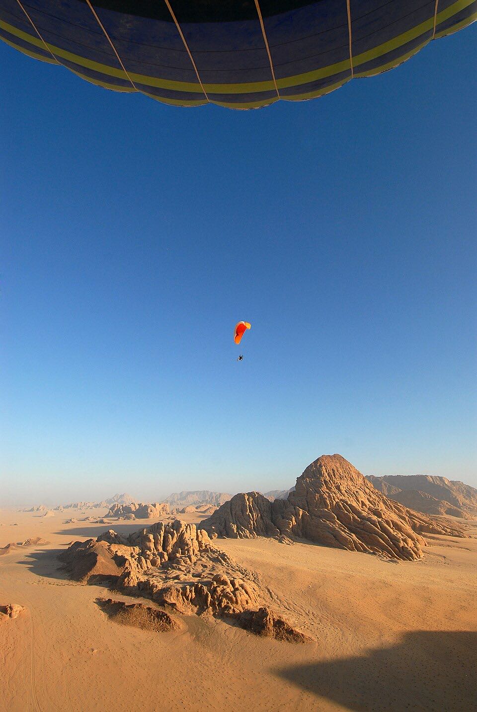 View from a hot air balloon basket over Wadi Rum, the envelope overhead and red desert below at sunrise