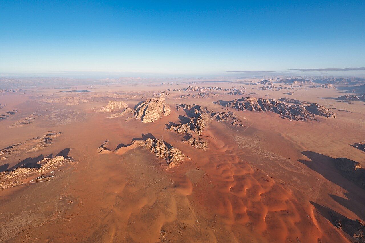 Aerial view of Wadi Rum's sandstone formations and red sand in early morning light
